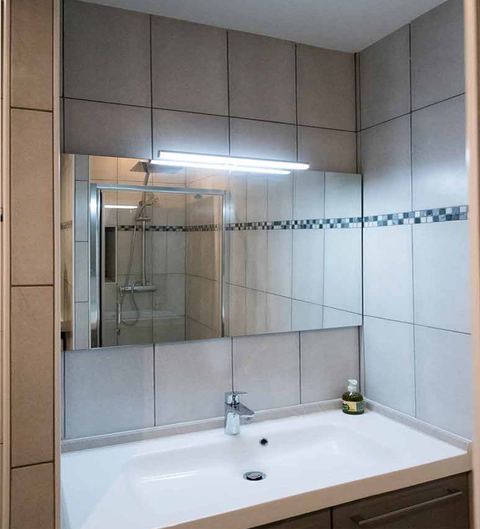 Vasque, miroir éclairé et carrelage moderne de la salle de bains